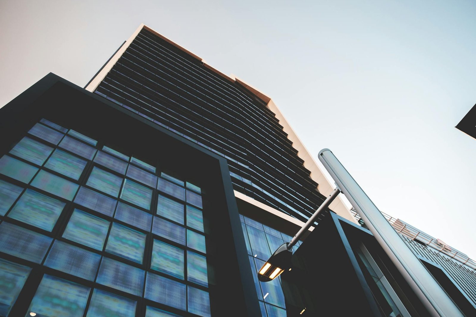 From below of modern tall business center with square shaped windows on street with contemporary streetlight